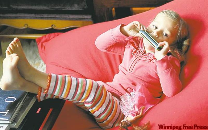 Five-year-old Hattie McCullough plays a tune on her harmonica while relaxing in a Lotus Lounger. 