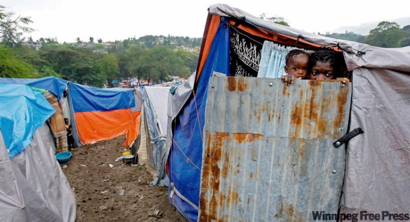 A woman and her baby peer out from their door at a camp for earthquake survivors set up in the Petionville Golf Club, Haiti.