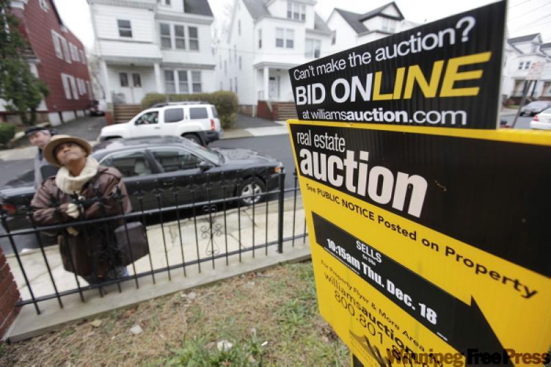 A prospective bidder examines the exterior of a home up for auction.