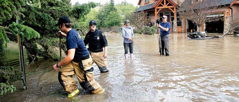 Firefighters check on homes as residents and volunteers are in flood clean up mode in Calgary last summer.