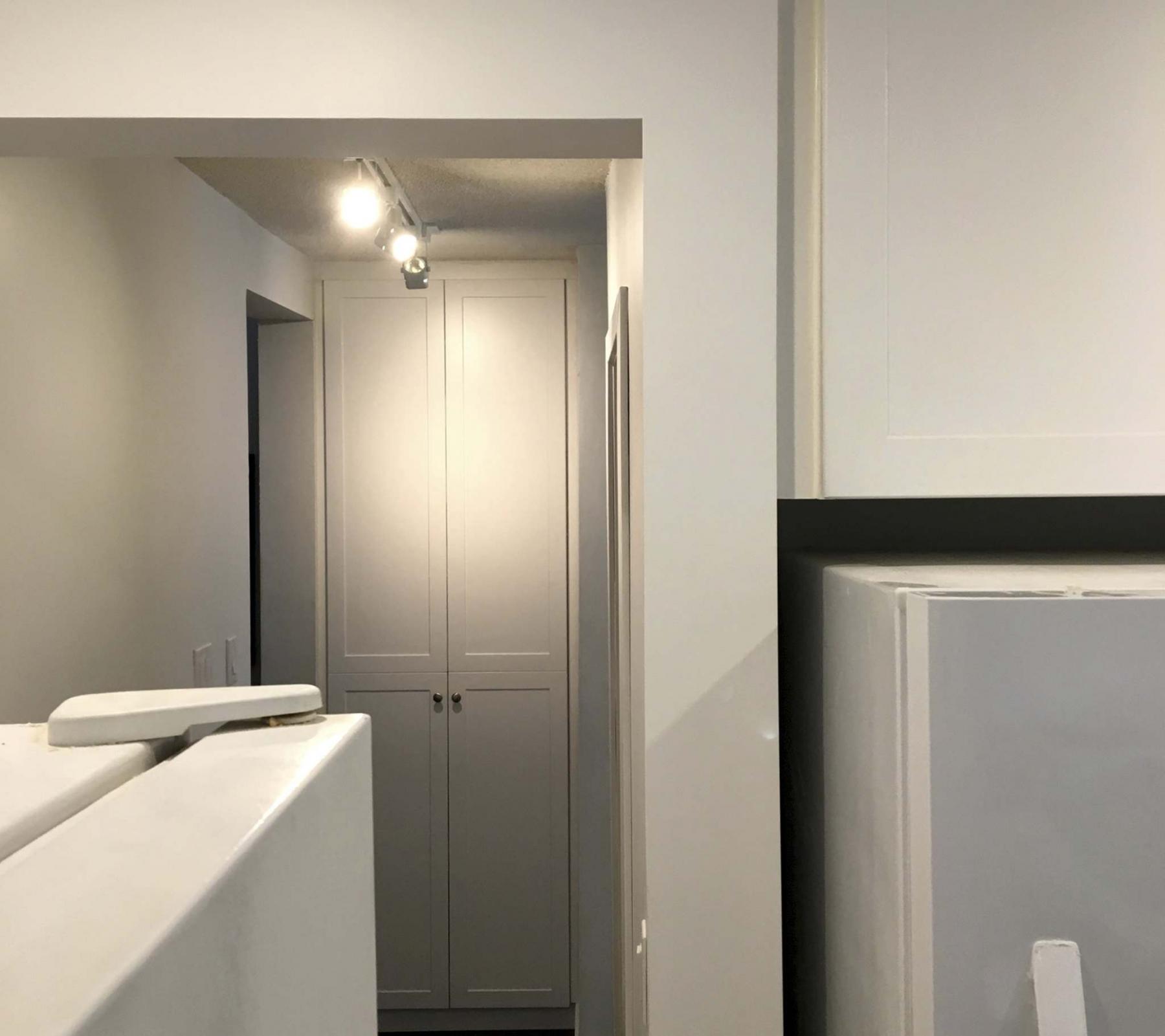 <p>Because the cupboard/pantry matches the new kitchen cupboards, it appears as a mere extension of the kitchen space even though it is located at the other end of the hall. </p>