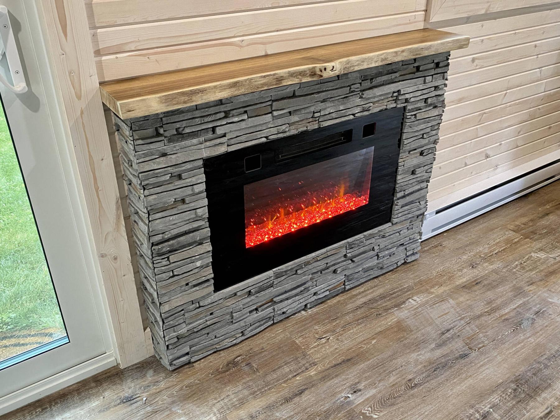  <p>Photos by Marc LaBossiere / Winnipeg Free Press</p>
                                <p>An electric wall-mount fireplace is recessed within a structure sheathed in faux-stone, topped with a live-edge wooden mantle.</p> 