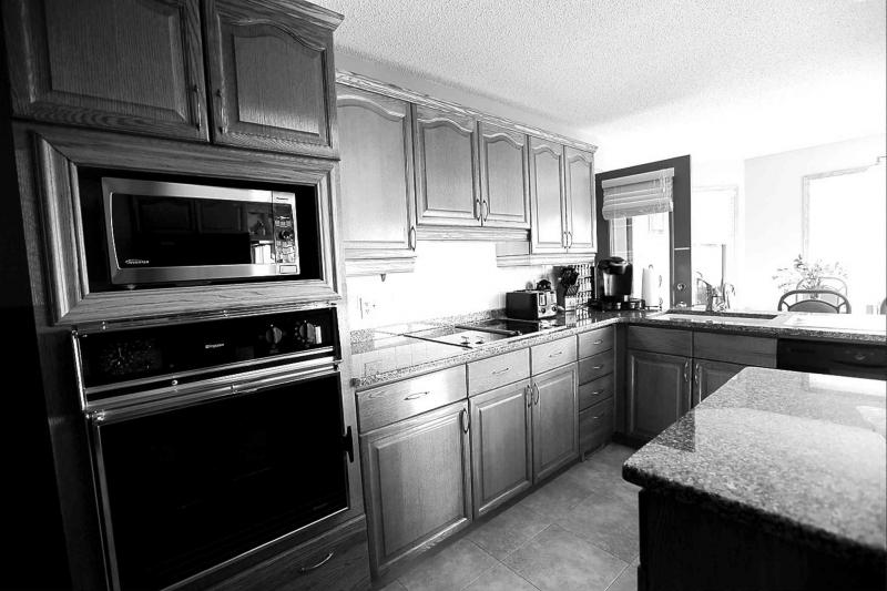 A huge 24-foot by 14-foot kitchen is bright, sunny and has a mid-sized island, wide aisles, granite countertops, tan tile floor and natural oak cabinets.