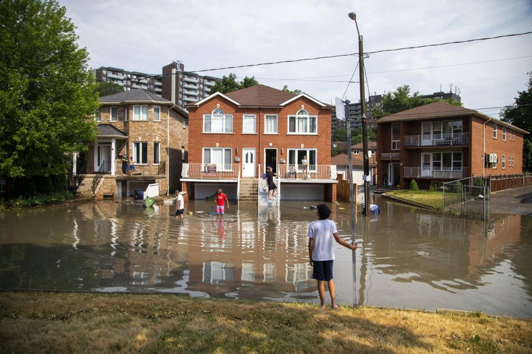  Neighbours deal with the flooding on Cordella Avenue after a severe thunderstorm caused localized flooding in Toronto on Wednesday, July 8, 2020. THE CANADIAN PRESS/Carlos Osorio 