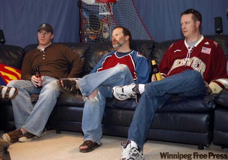 Tom Bruce, Joe Stone and Eirik Thune Larson watch college hoops on the big-screen in Stone's basement turned man cave.