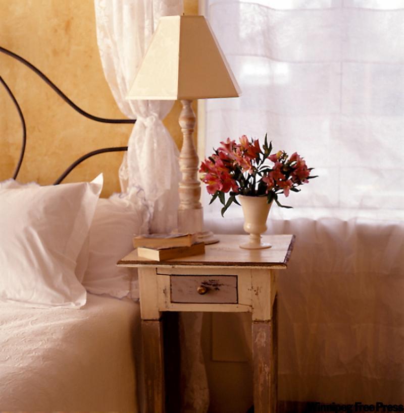 Weathered or antiqued walls and an aged bedside table contribute an old-world feel reminiscent of Provence.