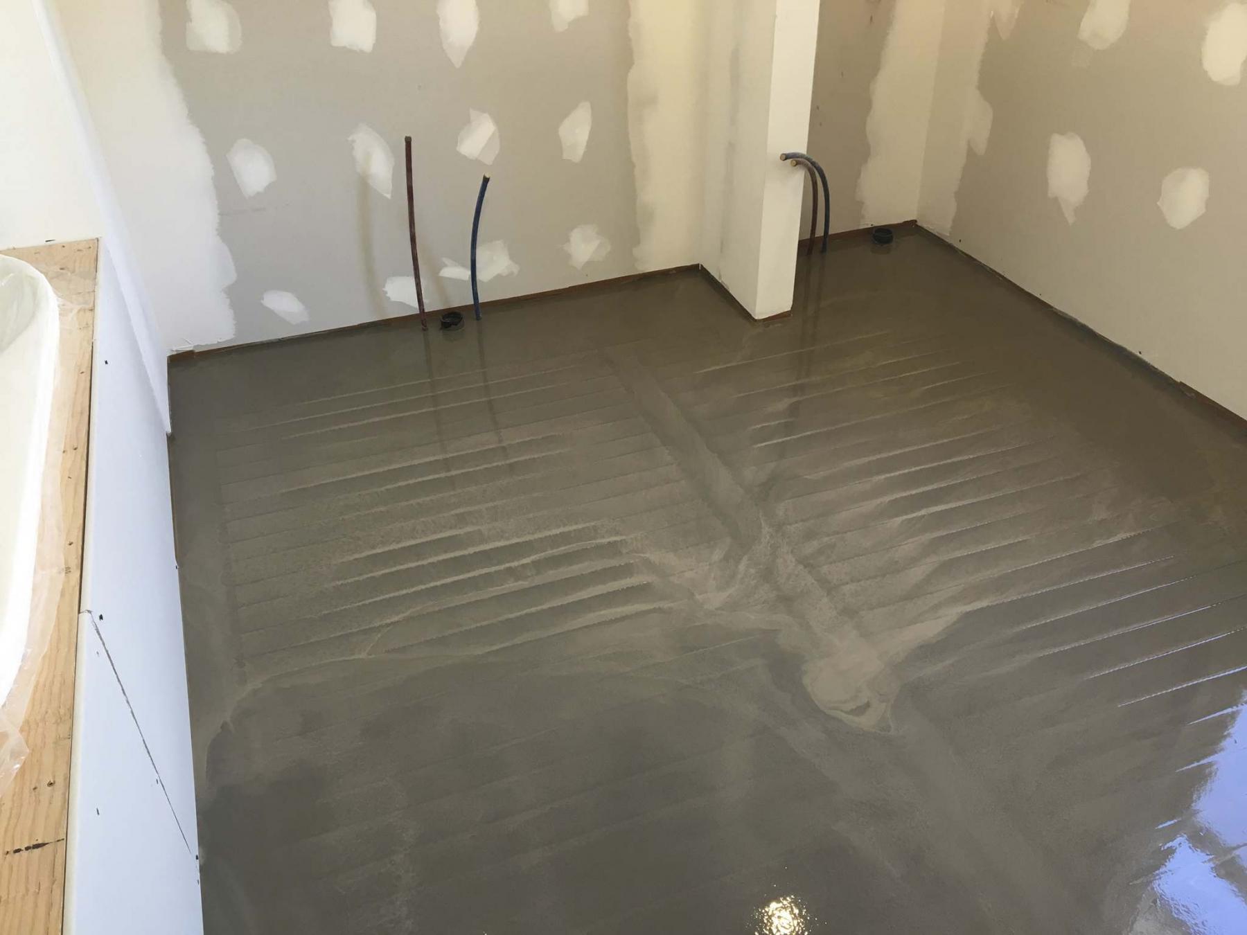 <p>The self-levelling concrete was forced into the corners and trowelled over the entire floor to ensure the heating coils were completely submerged.</p>