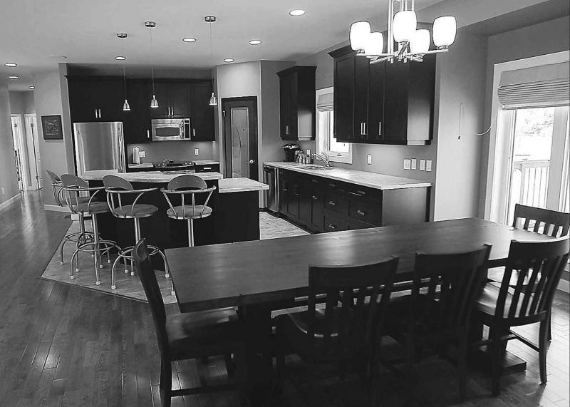 The kitchen, with its U-shaped island and dark cabinets, flows into the dining area which can easily hold a table for 10.