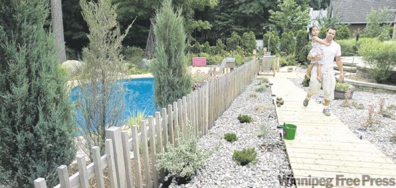 Danny Roberge and daughter Zia walk along one wooden walkway in their garden.
