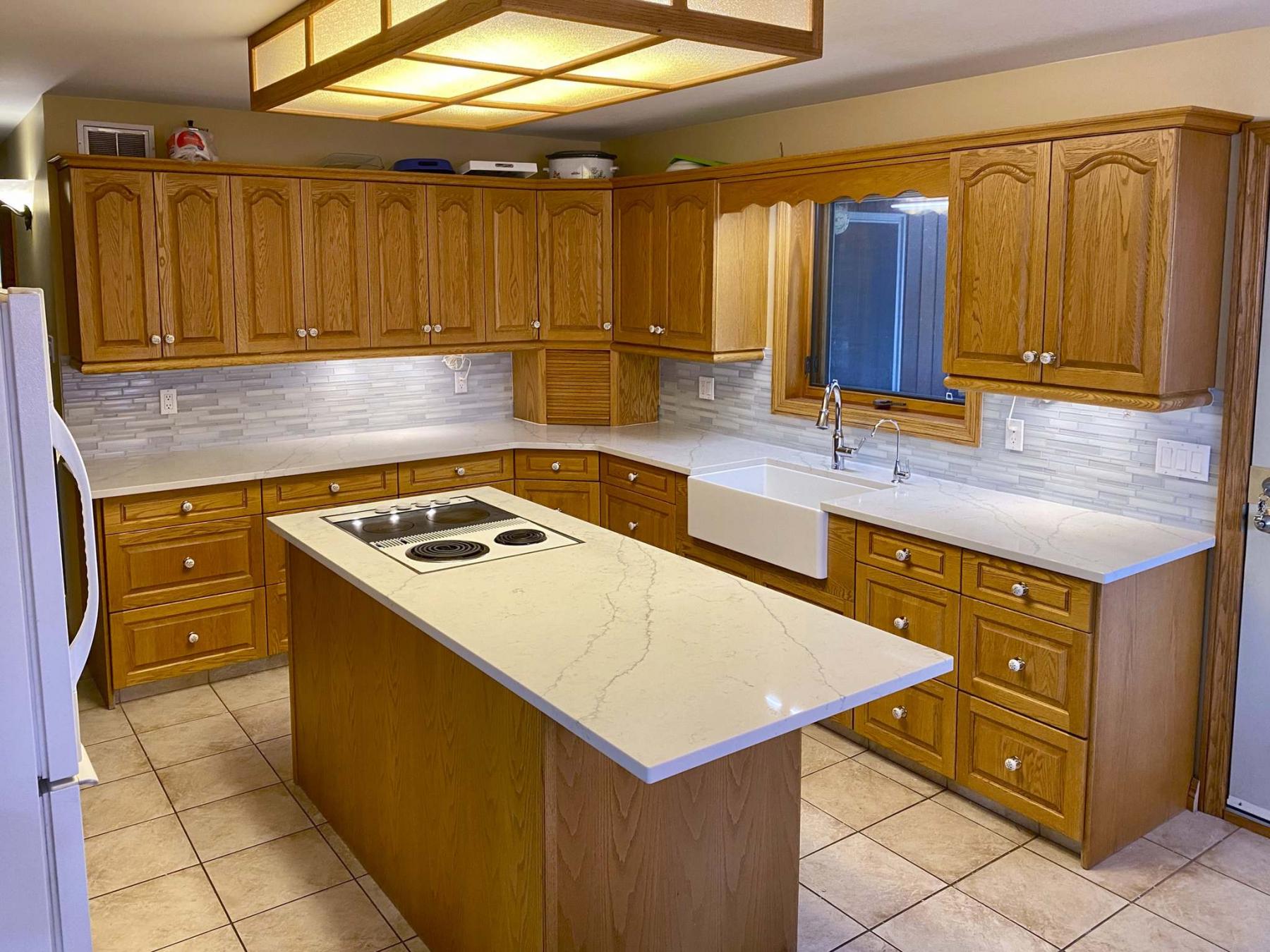 <p>Minor alterations made to the existing cupboards cater to the newly introduced apron sink and faucets, white quartz countertops and sleek glass-tile mosaic backsplash.</p></p>