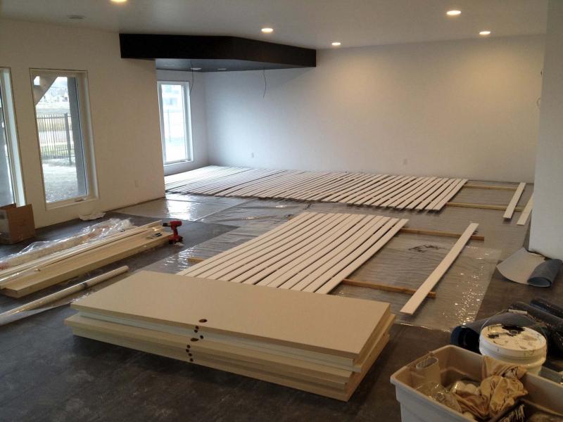 <p>rec-room space, far corner protrusion ceiling boxing visible in black, laminate installed, casings and baseboards (and doors) laid out for painting</p>