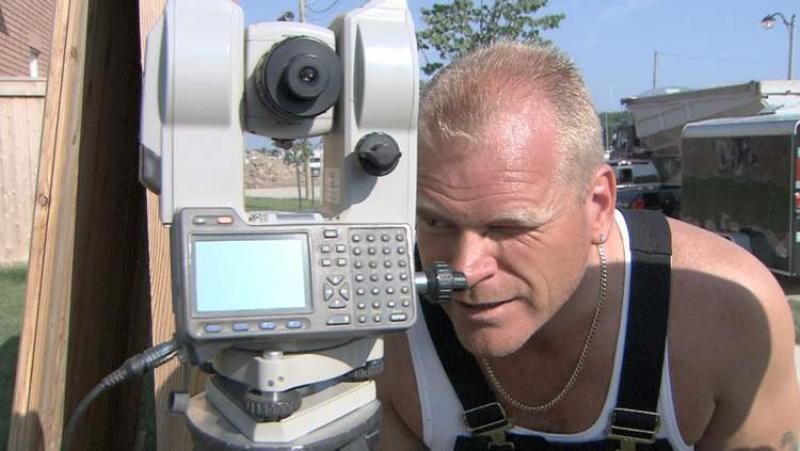 Mike Holmes checks a land survey to maintain the slope of a drainage easement. 
