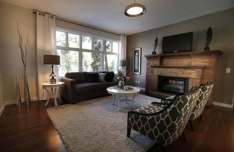 <p>The living room in the main-floor condo has a large picture window and an electric brick fireplace</p>