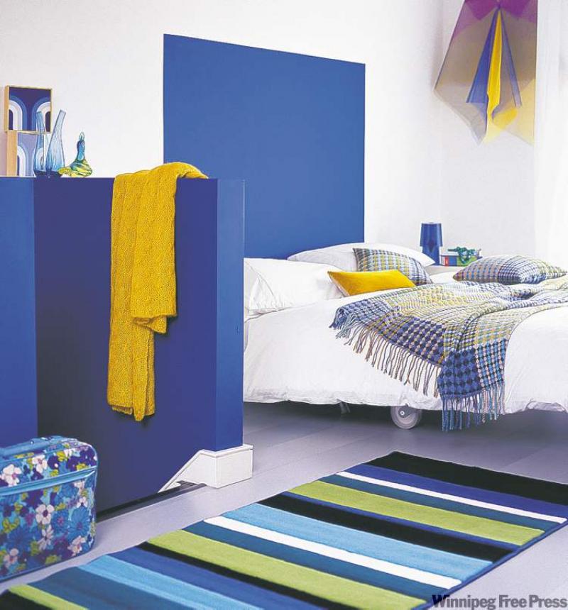 By painting a bright blue square at the head of the attic bedroom, the bed was given the illusion of a headboard as well as a sense of drama. The strong colour was carried over to the partial wall, which gives the room extra pizzazz.