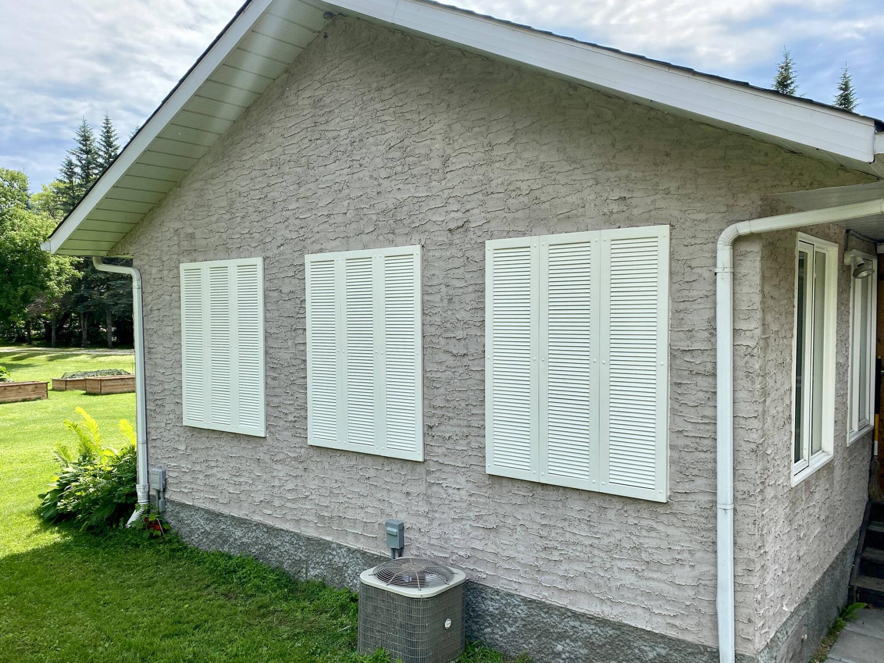 <p>Three sets of three faux window shutters cleverly conceal the old abandoned window openings set in stucco.</p>