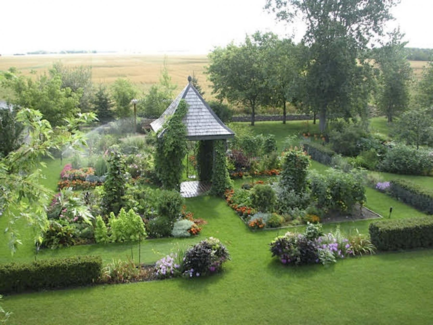 <p>A garden house sits in the centre of a parterre-like garden planted with perennials and vegetables.</p>