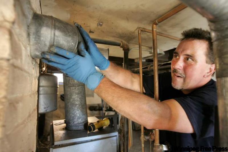 Oil burner technician John Brady, of Scituate, Mass., adjusts the furnace flue on an oil-burning furnace in the basement of a home, in Quincy, Mass.