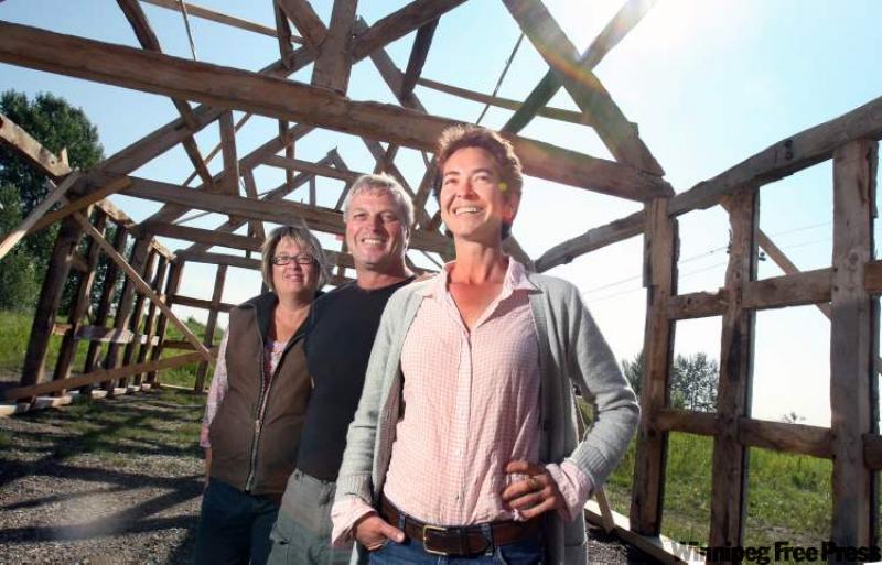 Left to right: Marla Brown and Rod Brown of Crazy Creek Timber Frames, and Monique Beaumont stand inside of a timber frame construction that was moved from England to be reconstructed in Okotoks, Alberta.