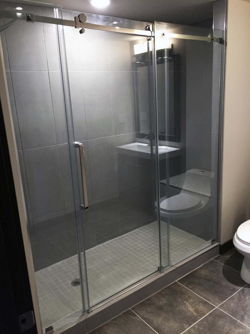 <p>Photos by Marc LaBossiere / Winnipeg Free Press</p><p>In this bathroom reno, the toilet and vanity (left) are set along the far wall. The oversized three-piece barn-style glass shower door (right) showcases the shower stall tiling, as well as the bench along the back wall. </p>