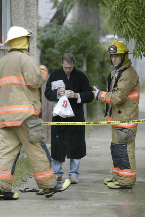 John Woods / Winnipeg Free Press / August 4 2006 - 060804 - Firefighters talk to a resident of  315 Rue de la Cathedral.  Police and firefighters were called to a fire at the location                   Friday, August 4/06.