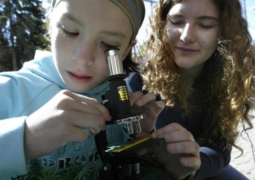 John Woods / Winnipeg Free Press / September 23, 2006 - 060923 - Anneliese Schoppe, a U of Winnipeg student, assists ten year old Gloria Luna look at a mosquito wing in a microscope at the Spence Neighbourhood Association's Inspiration Market on Spence Street Saturday, September 23/06.   The purpose of the event is to showcase the community's talents through a series of workshops and performances.