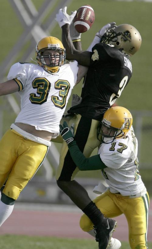 John Woods / Winnipeg Free Press / September 23, 2006 - 060923 - U of Manitoba Bison's Randolph Simmons (3) goes up for the pass against Alberta's Scott Stevenson (33) and Trevor Moen (17) in second quarter action Saturday, September 23/06.