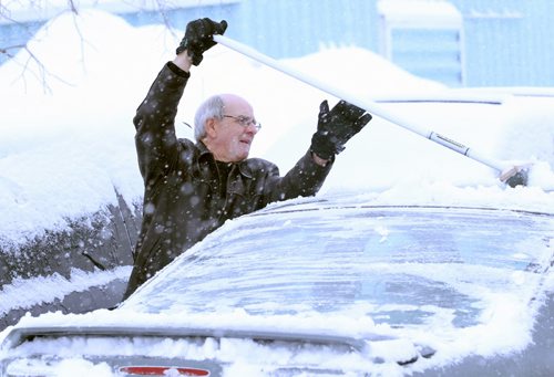 Brandon Sun 15122010 Tom Mowbray of Cartwright uses his curling broom to brush thick snow off of his car after his Masters Super League match at the Brandon Curling Club on Wednesday. (Tim Smith/Brandon Sun)
