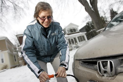 TREVOR HAGAN / WINNIPEG FREE PRESS - Kate Tate plugs her car in on Lenore Street. She runs her extension cord above the sidewalk and wraps it around a tree so that it is out of the way of plows and pedestrians. 10-12-20