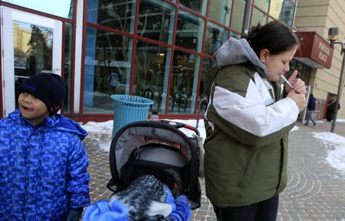 MIKE.DEAL@FREEPRESS.MB.CA 101230 - Thursday, December 30, 2010 - Streeter for story about changes to the warnings on cigarett boxes. Angela Delaronde with her two kids lights up outside Portage Place Shopping Centre. MIKE DEAL / WINNIPEG FREE PRESS
