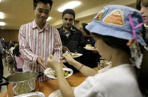 John Woods / Winnipeg Free Press / October 5, 2006 - 061005 -Siil Park, from Korea is served some turkey by nine year old Emily Isaac at a Thanksgiving dinner put on for immigrants at the International Centre Thursday, Oct. 5/06.  The Girl Guides helped with fund raising and serving of the meal.