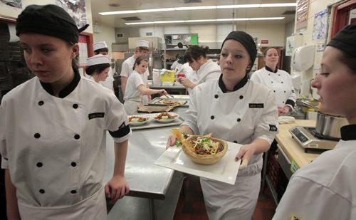 MIKE.DEAL@FREEPRESS.MB.CA 110205 - Saturday, February 05, 2011 - Whitney Pull (centre) with fellow students from Stonewall Collegaite move their finished dish, Bison chili with cheese, during the Localvore Iron Chef Cook-off at Sturgeon Heights Collegiate on Saturday. The cook-off involving high school students from across Manitoba competed in teams using local ingredients and were paired up with professional chef mentors. MIKE DEAL / WINNIPEG FREE PRESS