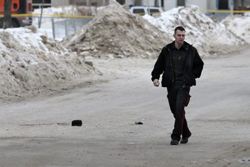 MIKE.DEAL@FREEPRESS.MB.CA 110205 - Saturday, February 05, 2011 - The scene of the double homicide that occured around 2:30 a.m. on Ellen Street at Elgin Avenue just outside the Manitoba Housing block at 425 Elgin. A Winnipeg police officer walks past the pool of blood, hat, can of bear spray and spent bullet casings. See Bill Redekop story. MIKE DEAL / WINNIPEG FREE PRESS