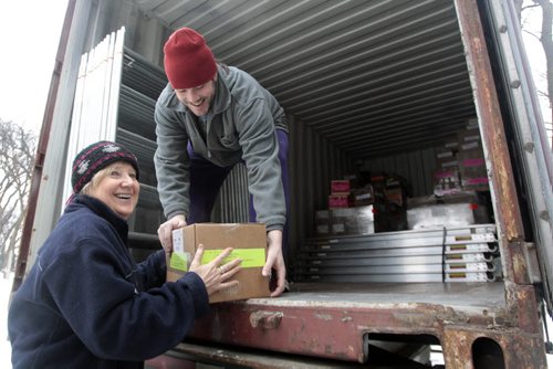 MIKE.DEAL@FREEPRESS.MB.CA 110217 - Thursday, February 17, 2011 - Friends and volunteers, Barb Findlay hands over a box of books to Greg Barker as the container slowly starts to fill up. Kathy Knowles and her volunteer army in Winnipeg are sending their last container of books to children in Ghana. Knowles and her Osu Children's Library Fund, a non-profit organization, have helped more than 190 libraries in Africa. Out of her command centre on the third floor of her River Heights home, Knowles works full time as the volunteer program director. She has helped build six large libraries serving thousands of children in Accra, Ghana, and the fund provides books, literacy classes, food and scholarships for deserving library members. MIKE DEAL / WINNIPEG FREE PRESS