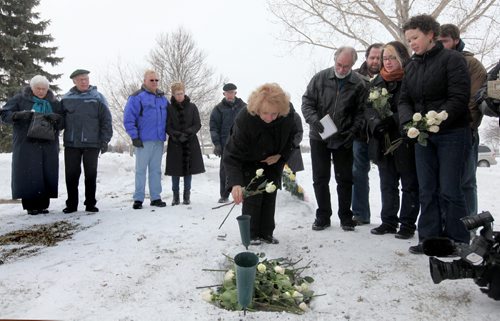 Ruth Bonneville Winnipeg Free Press Feb 19, 2022 Local, WIlma Derksen lays white roses on her daughter Candace's grave while her husband Cliff (her left) family and friends look at ceremony Saturday morning.