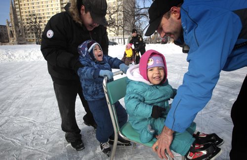 MIKE.DEAL@FREEPRESS.MB.CA 110223 - Wednesday, February 23, 2011 - Bruce Patrick (left) with kids Connor Robinson, 4 (skating), and Angela Patrick, 3 (on chair), while a Winnipeg Police Cadet helps out during the 2nd annual Skates and Badges which was held at Central Park from 3:00 pm until 6:00 pm on Wednesday. Members of the WPS Patrolmen Hockey Team were also on hand to help and encourage learners. MIKE DEAL / WINNIPEG FREE PRESS