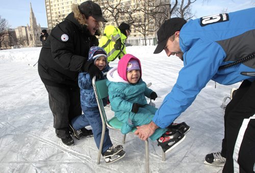 MIKE.DEAL@FREEPRESS.MB.CA 110223 - Wednesday, February 23, 2011 - Bruce Patrick (left) with kids Connor Robinson, 4 (skating), and Angela Patrick, 3 (on chair), while a Winnipeg Police Cadet helps out during the 2nd annual Skates and Badges which was held at Central Park from 3:00 pm until 6:00 pm on Wednesday. Members of the WPS Patrolmen Hockey Team were also on hand to help and encourage learners. MIKE DEAL / WINNIPEG FREE PRESS