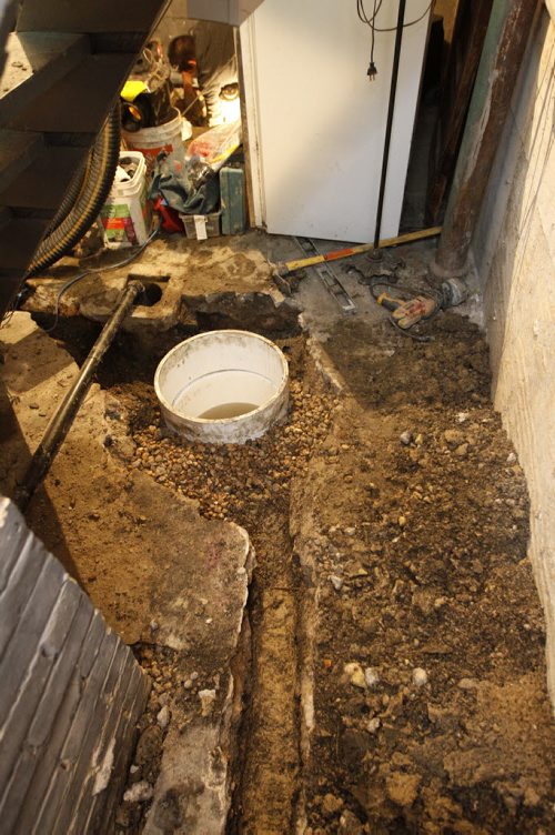 TREVOR HAGAN / WINNIPEG FREE PRESS - A freshly dug sump pit. Top, Darrel Campbell of Basement Systems Winnipeg works on a backwater valve installation in Linda Pearns' basement.  11-02-23