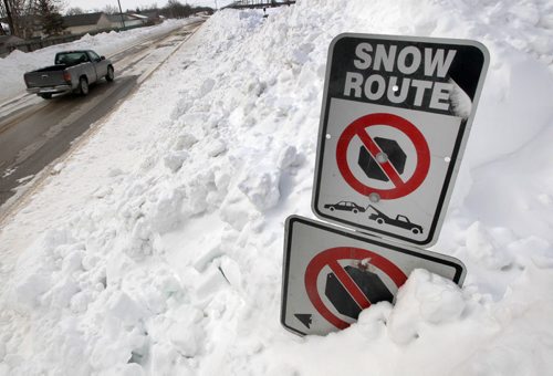 JOE.BRYKSA@FREEPRESS.MB.CA Local- (Standup photo)-  Massive snowbanks to the top of street signs  are piled on the  side of the road on Saskatchewan Ave in Winnipeg Sunday afternoon after crews have cleared roads after this weekends blizzard-   JOE BRYKSA/WINNIPEG FREE PRESS- Mar 13, 2011
