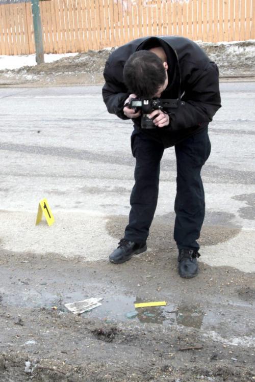MIKE.DEAL@FREEPRESS.MB.CA 110322 - Tuesday, March 22, 2011 - The Winnipeg Police had an address on Mandalay Drive surrounded following a police involved shooting at another address in the city. A dodge truck was located at the address with a bullet hole in its side and a smashed passenger-side window. Here a ident officer photographs broken glass from the truck window. MIKE DEAL / WINNIPEG FREE PRESS