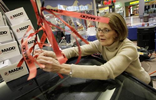 John Woods / Winnipeg Free Press / October 30, 2006 - 061030 - Bev Murfitt of MADD ties a ribbon on a wrecked car in Grant Park Shopping Centre Monday Oct 30/06.   MADD launched their annual Red Ribbon Campaign today at the mall.