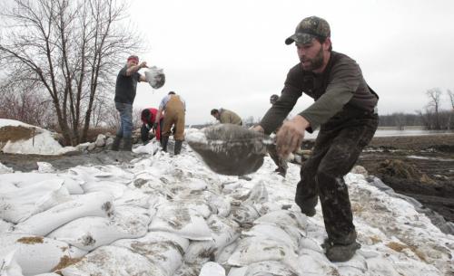 MIKE.DEAL@FREEPRESS.MB.CA 110409 - Saturday, April 09, 2011 - Will Truman (right) spent yesterday filling sandbags, today putting them in place to close off the dike that surrounds his property on Hwy 200 just north of St. Adolphe, MB. The overflowing Red River can be seen in the background.  MIKE DEAL / WINNIPEG FREE PRESS
