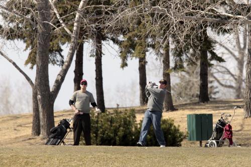 MIKE.DEAL@FREEPRESS.MB.CA 110420 - Wednesday, April 20, 2011 - About a dozen brave souls took to the links at Harbour View Golf Course on opening day today. Ben Wirch drives the ball off the ninth tee while friend Elwyn Beauvais watches. MIKE DEAL / WINNIPEG FREE PRESS