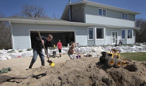 MIKE.DEAL@FREEPRESS.MB.CA 110514 - Saturday, May 14, 2011 -  A toy truck sits in a pile of sand while Jonathan Allard, 12 (left) and brothers Justin, 9 (centre), Caleb, 7 (right) fill up buckets to take to the back yard to help with the protection of the house close to the Hoop and Holler bend of the Assiniboine River. See Bruce Owen story. MIKE DEAL / WINNIPEG FREE PRESS