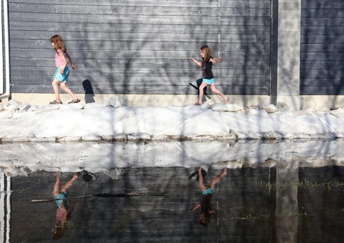 Brandon Sun 15052011 Sisters Emmalee and Sadies Poczik are reflected in the flood waters as they play along the sandbag dike protecting their grandparents home on Grand Valley Rd. on Sunday evening. (Tim Smith/Brandon Sun)