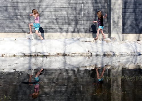 Brandon Sun 15052011 Sisters Emmalee and Sadies Poczik are reflected in the flood waters as they play along the sandbag dike protecting their grandparents home on Grand Valley Rd. on Sunday evening. (Tim Smith/Brandon Sun)