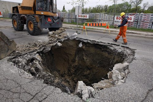KEN GIGLIOTTI / WINNIPEG FREE PRESS / May 27 2011 - Stdup - a large sink hole gave way on Archibald St  causing the closure of Archibald ST. from Marion St.  to Messier - the sinkhole is 16ftx16ft. by 15 ft deep and occupies  all of the northbound lane and part of the southbound lane , city crews are at the scene  to repair the damage . The hole location is at approx. 436 Archilbald   and the roads are closed  to through traffic although local traffic can get to businesses up to and  either side  of the hole .
