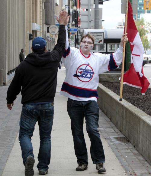 MIKE.DEAL@FREEPRESS.MB.CA 110531 - Tuesday, May 31, 2011 -  Hockey fans gathered at Portage and Main to celebrate the return of the NHL to Winnipeg, MB. Cassidy Dankochik gets a high-five from a passer-by while on his way to Portage and Main. MIKE DEAL / WINNIPEG FREE PRESS