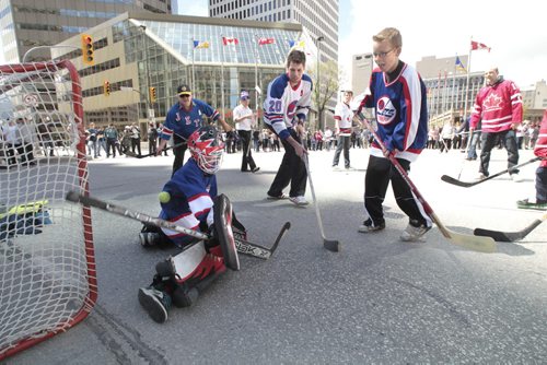MIKE.DEAL@FREEPRESS.MB.CA 110531 - Tuesday, May 31, 2011 -  Hockey fans gathered at Portage and Main to celebrate the return of the NHL to Winnipeg, MB. Matt Guenther, 12, plays goalie during a massive pick-up hockey game. MIKE DEAL / WINNIPEG FREE PRESS