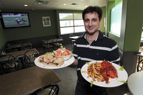 MIKE.DEAL@FREEPRESS.MB.CA 110601 - Wednesday, June 01, 2011 -  Restaurant review George Dasilva, manager, with a Bifana sandwich with house salad and Half-chicken and homemade fries. MIKE DEAL / WINNIPEG FREE PRESS