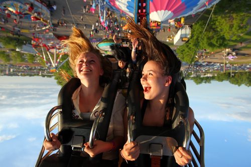 Brandon Sun 10062011 Kate Lawford and Taylor Aucoin get an upside-down look at the Manitoba Summer Fair from the midway ride The Fireball on Saturday evening. (Tim Smith/Brandon Sun)